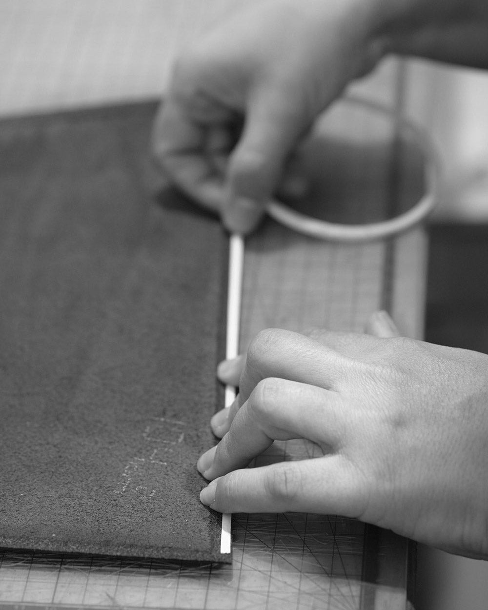 A close up of two hands applying double sided tape to a leather panel.