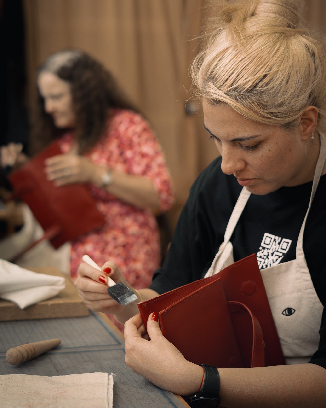 Woman applying burnishing agent to the edges of the bag with a focus on her hands and face, blurred background